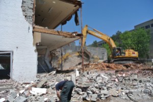 An excavator topples walls and gathers rubble toward the end of demolition of the Ruderman's Building.